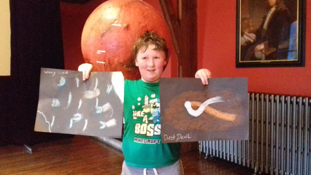 Yes, this boy did an impactful drawing of a Martian Dust Devil. He also holds a drawing of sand moving across the surface of the planet.