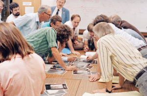 Members of the Voyager science team pore over fresh images of Neptune's moon Triton as data from Voyager 2 stream into JPL in August 1989. Photo by: D. Patterson and B. Rowe. Courtesy NASA/JPL-Caltech.