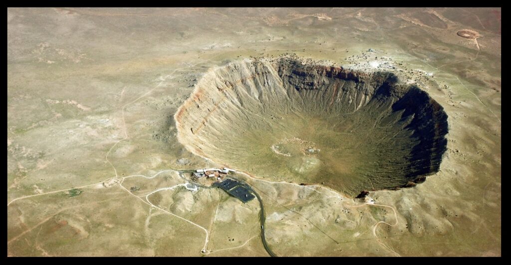 Meteor Crater in Arizona.  From a NEO that got a little too close, releasing a few megatons of energy when it hit.  Note the road and the parking lot in the foreground.  Photo from Shane Torgerson, Wikimedia Commons.